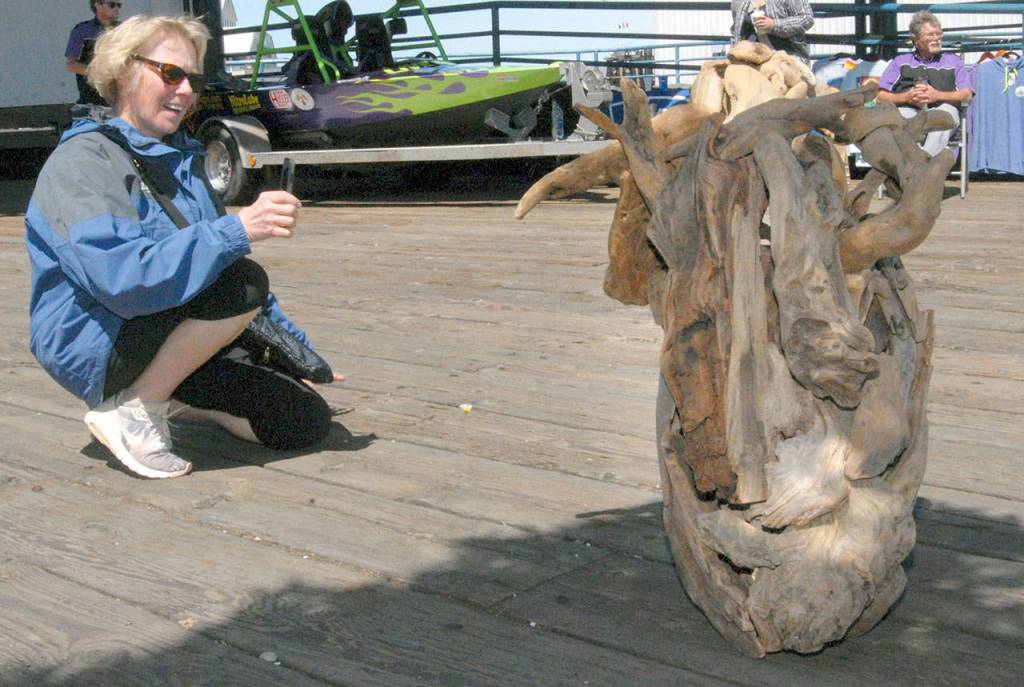 Linnea Weida of Litchfield, Minn., examines a driftwood sculpture placed along a walkway at Port Angeles City Pier. (Keith Thorpe/Peninsula Daily News)