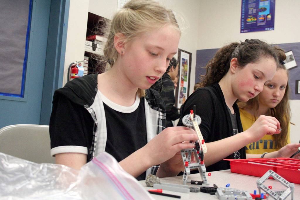 Zoey Sonandre, Tallulah Sebastian and Juliette OHara, sixth-graders from Blue Heron Middle School in Port Townsend, use Lego Mindstorm pieces to build a rover as part of their simulation of the Apollo 11 mission. The NASA Challenge included piloting a drone and coding a control device that would move a Lego rover across a mat that displayed the surface of the moon. (Brian McLean/Peninsula Daily News)
