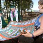 Louisa Monger, a teacher at Dry Creek School and formerly at Jefferson School, right, shows off a quilt made 10 years ago from squares created by her students, including Port Angeles High School seniors Charles Krause, left, and Tristian Turner, prior to commencement ceremonies on Friday evening at Port Angeles Civic Field. More than 230 students were scheduled to become part of the Class of 2019. (Keith Thorpe/Peninsula Daily News)
