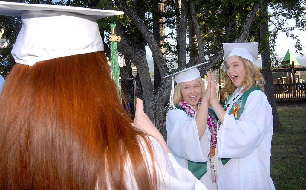 Port Angeles High School senior Rachel Hendry, left, takes a photo of classmates Christine Beirne and Charlotte Hertel at Erickson Playfield prior to Fridays commencement ceremony at nearby Civic Field. More than 230 students were scheduled to become part of the Class of 2019. (Keith Thorpe/Peninsula Daily News)