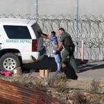 In this Dec. 15, 2018, file photo, Honduran asylum seekers are taken into custody by U.S. Border Patrol agents after the group crossed the U.S. border wall into San Diego, Calif., seen from Tijuana, Mexico. (Moises Castillo/The Associated Press)