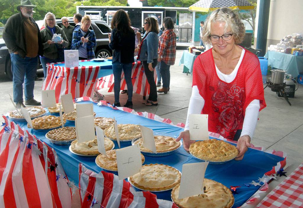 Pie contest volunteer Janet Atkinson adds an apple pie to a table of other pies up for judging during Thursdays pie contest at Port Angeles City Pier. (Keith Thorpe/Peninsula Daily News)
