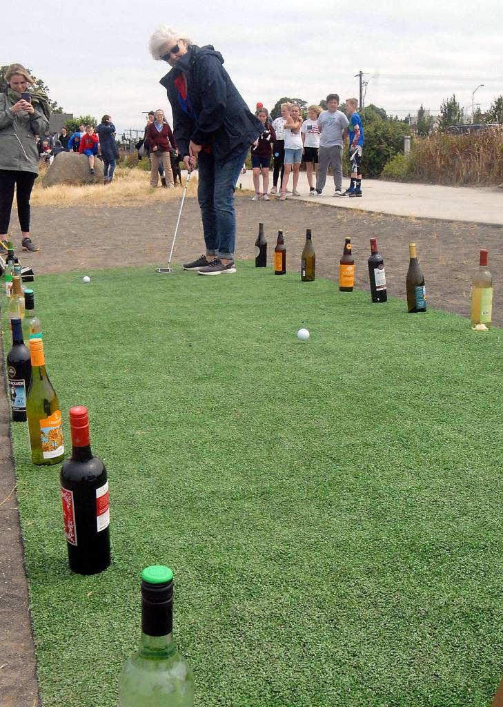 Lisa Thomson of Port Angeles putts to win a bottle of wine at a miniature golf hole at Pebble Beach Park to benefit Habitat for Humanity on Thursday in Port Angeles. (Keith Thorpe/Peninsula Daily News)