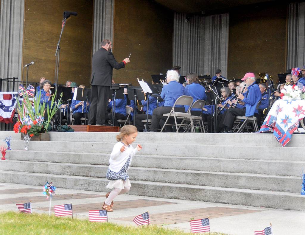 While her father Tyler Benedict directs the Sequim City Band, 2-year-old Amelia Benedict enjoys the music at the bands traditional 4th of July Concert on Thursday afternoon. (Mike Dashiell/Olympic Peninsula News Group)