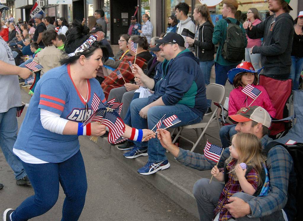 Kaylie Rinehart, a member of the Port Angeles Lions Club, left, passes out American flags to parade-goers on Thursday evening. (Keith Thorpe/Peninsula Daily News)