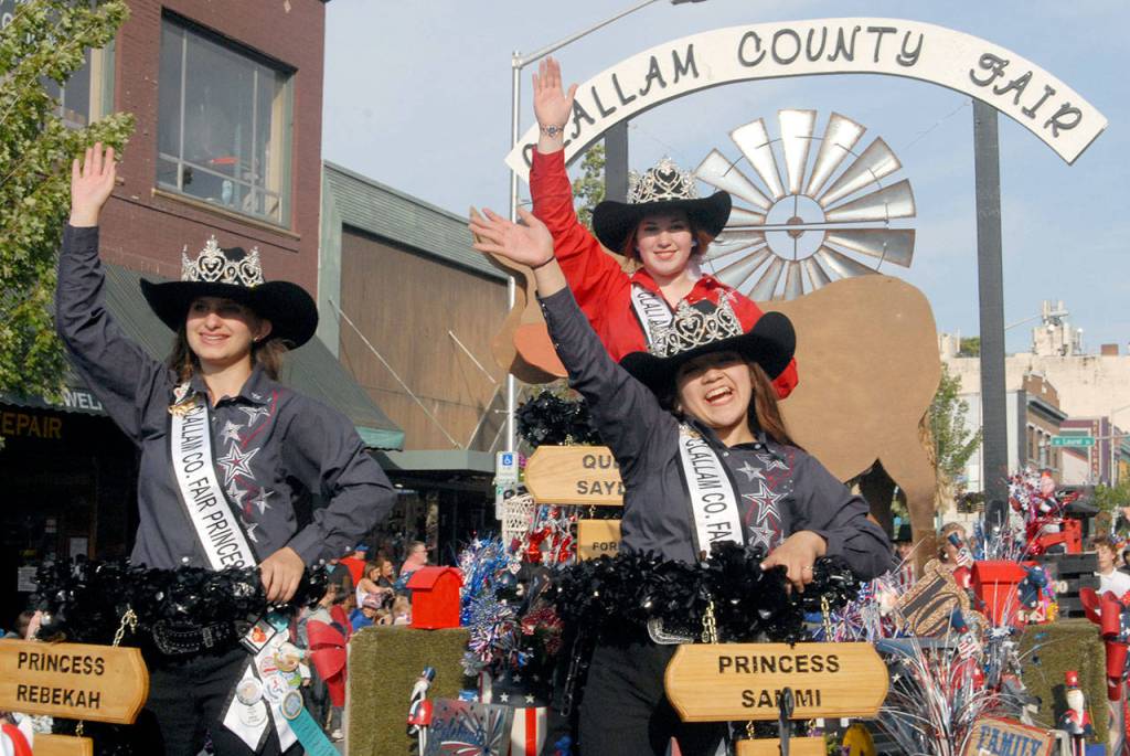 Clallam County Fair royalty, from left, Princess Rebekah Parker, Queen Saydee Peters and Princess Sammi Bates wave to the crowds from their float on Independence Day. (Keith Thorpe/Peninsula Daily News)