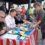 Pie contest judges, from left, former Port Angeles City Manager Dan McKeen, Clallam County Prosecuting Attorney Mark Nichols and former Port Angeles police Chief Terry Gallagher receive slices from organizers Leslie Robertson and Edna Peterson, right, during Thursdays pie rivalry between the Port Angeles fire and police departments. (Keith Thorpe/Peninsula Daily News)