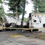 The shells of two mobile homes and an automobile are guarded behind police tape Saturday morning at the Welcome Inn RV Park in Port Angeles. (Keith Thorpe/Peninsula Daily News)