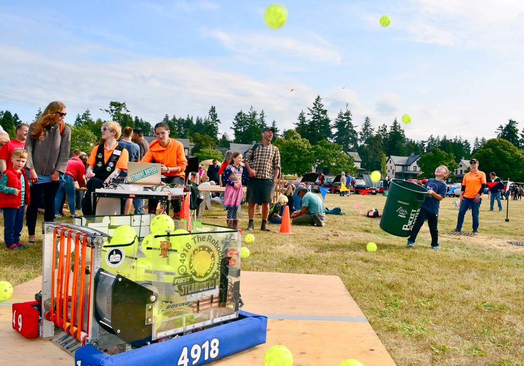 The Port Townsend robotics team, the Roboctopi, offer participants of all ages a chance to catch balls launched by one of its recent creations at the Old School 4th of July celebration in Port Townsend. (James Cook/for Peninsula Daily News)