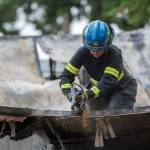 An ATF agent cuts through debris at the scene of a fire in Port Angeles, where the bodies of a mother and three children were found. (Jesse Major/Peninsula Daily News)