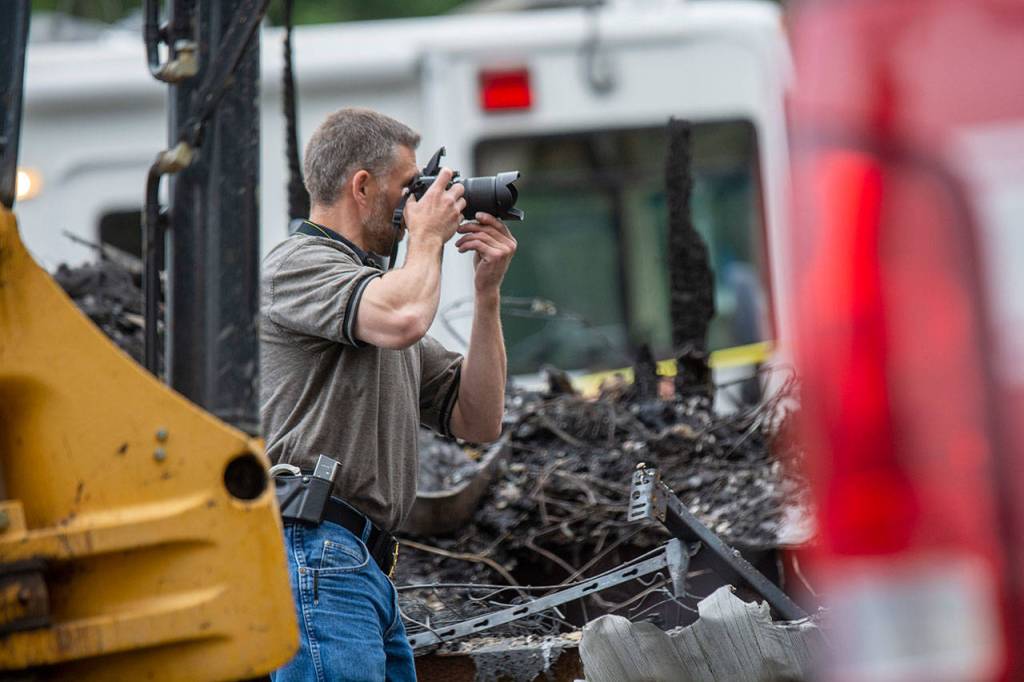 Clallam County Sheriffs Office Detective Josh Ley takes photos at the scene of a fire where the bodies of a mother and three young children were found. (Jesse Major/Peninsula Daily News)