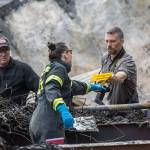 Clallam County Sheriffs Office Detective Josh Ley, right, hands an evidence marker to an ATF agent as investigators comb through the scene of a fire where the bodies of a mother and three children were found. (Jesse Major/Peninsula Daily News)