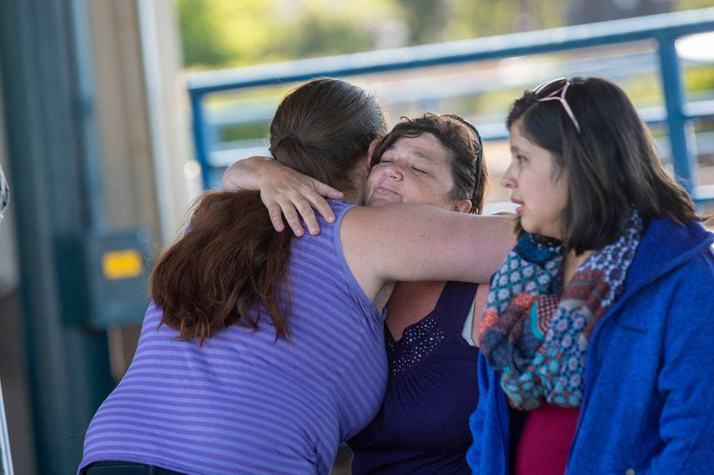 Holly Wright, a friend of Valerie Kambeitz and her children Lilly, Emma and Jayden Kambeitz, receives a hug during a vigil in their honor Monday. (Jesse Major/Peninsula Daily News)