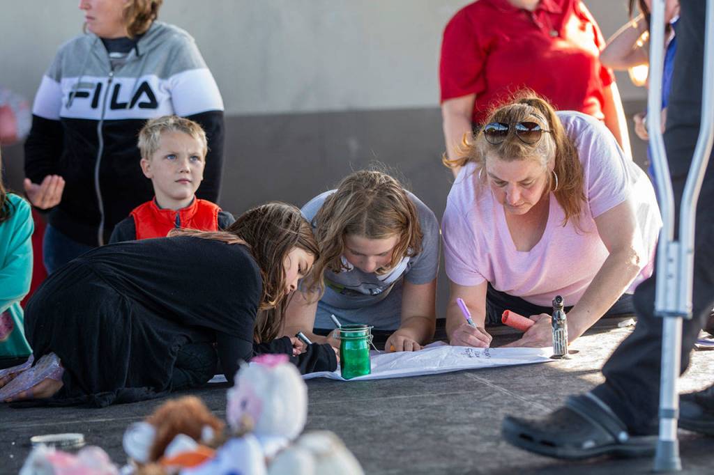 People leave notes on a sky lantern for Valerie Kambeitz and her children Lilly, Emma and Jayden Kambeitz during a vigil in their honor Monday. (Jesse Major/Peninsula Daily News)