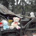 A memorial of teddy bears and flowers sits Wednesday atop a burned car near where the bodies of Valerie Kambeitz, 34, and her children, Lilly Kambeitz, 9, Emma Kambeitz, 6, and Jayden Kambeitz, 5, were discovered after a mobile home fire Saturday at the Welcome Inn RV Park in Port Angeles. (Keith Thorpe/Peninsula Daily News)