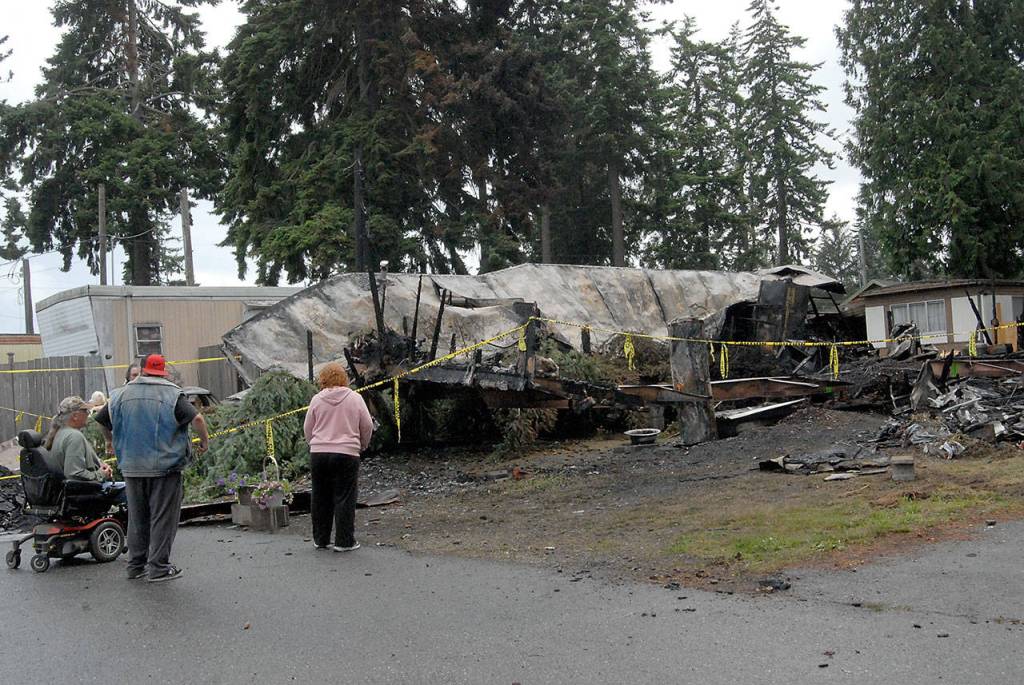 Neighbors gather at the scene Wednesday where the bodies of a mother and her three children were discovered after a fire that destroyed two mobile homes and two vehicles on Saturday at the Welcome Inn RV Park in Port Angeles. (Keith Thorpe/Peninsula Daily News)