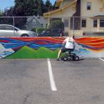 Port Angeles artist Todd Fischer works to convert a plain a retaining wall into a mural Friday at the Banbury Corner Childrens Center In Port Angeles. (Keith Thorpe/Peninsula Daily News)