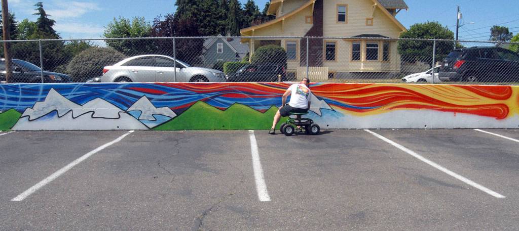 Port Angeles artist Todd Fischer works to convert a plain a retaining wall into a mural Friday at the Banbury Corner Childrens Center In Port Angeles. (Keith Thorpe/Peninsula Daily News)