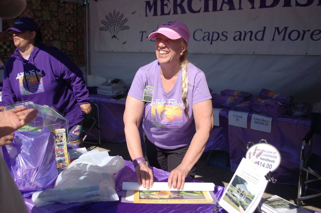 Ellen Riddell sells Sequim Lavender Growers Association merchandise at the Sequim Lavender Festival street fair in 2017. The Street Fair continues at Carrie Blake Community Park for the second summer this weekend. (Erin Hawkins/ Olympic Peninsula News Group)