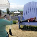 Brian Morrow of Omaha, Neb., lies in an oversize chair as his wife, Tammie Morrow, takes a cellphone photo at Olympic Lavender. (Keith Thorpe/Peninsula Daily News)