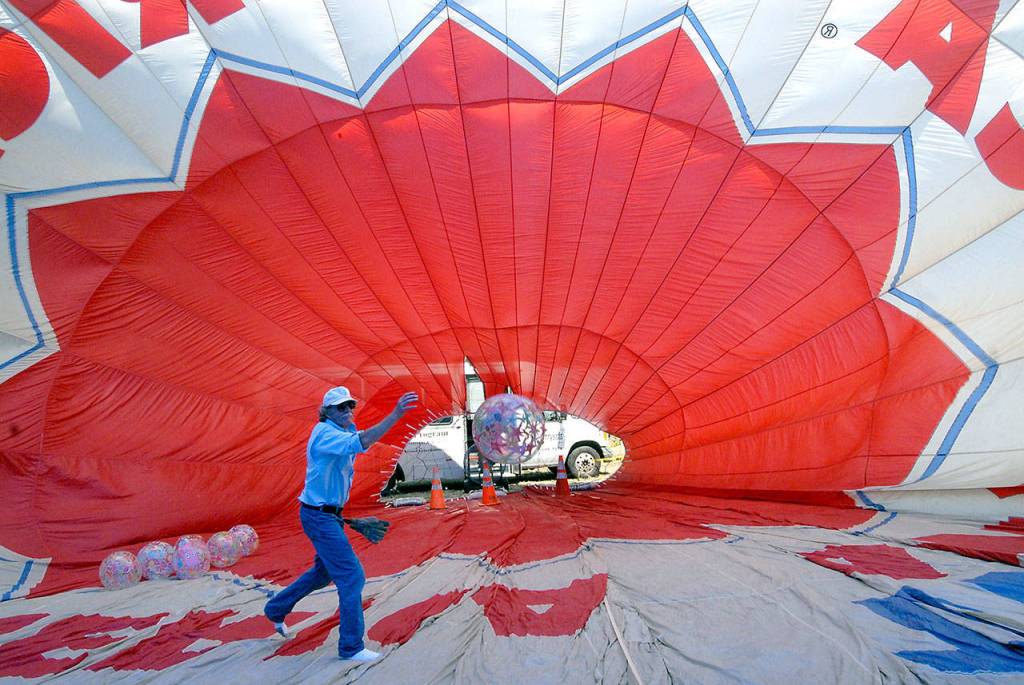 Jeff Terry, crew chief with the Dream Catcher Balloon project, tosses a ball in front of a fan used to inflate a decommissioned hot air balloon set up as a bounce house at the Olympic Lavender farm. (Keith Thorpe/Peninsula Daily News)