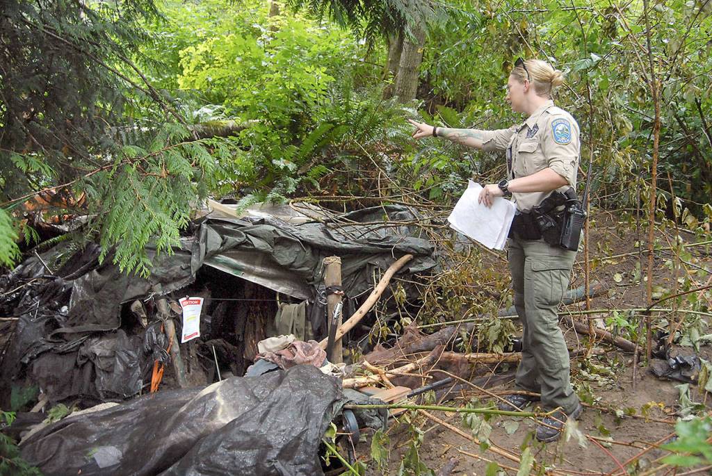 Officer Tierra Wessel of the Fish & Wildlife Police points out a shelter carved into a hillside on a fish and wildlife preserve near Morse Creek. (Keith Thorpe/Peninsula Daily News)