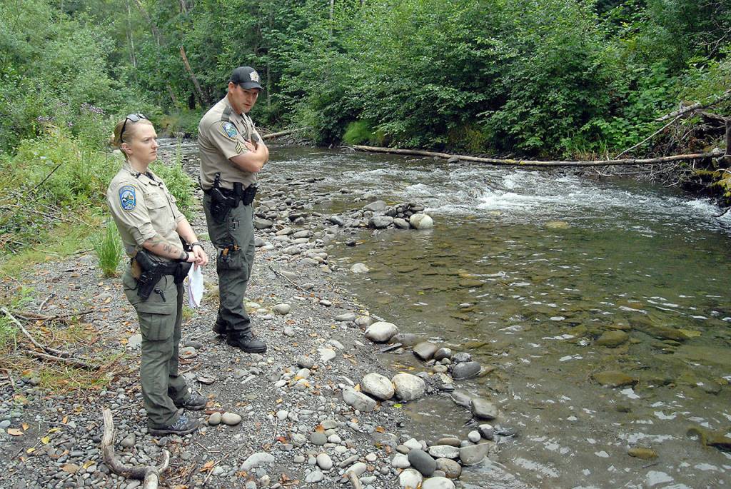 State Department of Fish & Wildlife Police Officer Tierra Wessel, left, and Sgt. Kit Rosenberger survey habitat damage to Morse Creek near a homeless camp east of Port Angeles on Friday. (Keith Thorpe/Peninsula Daily News)