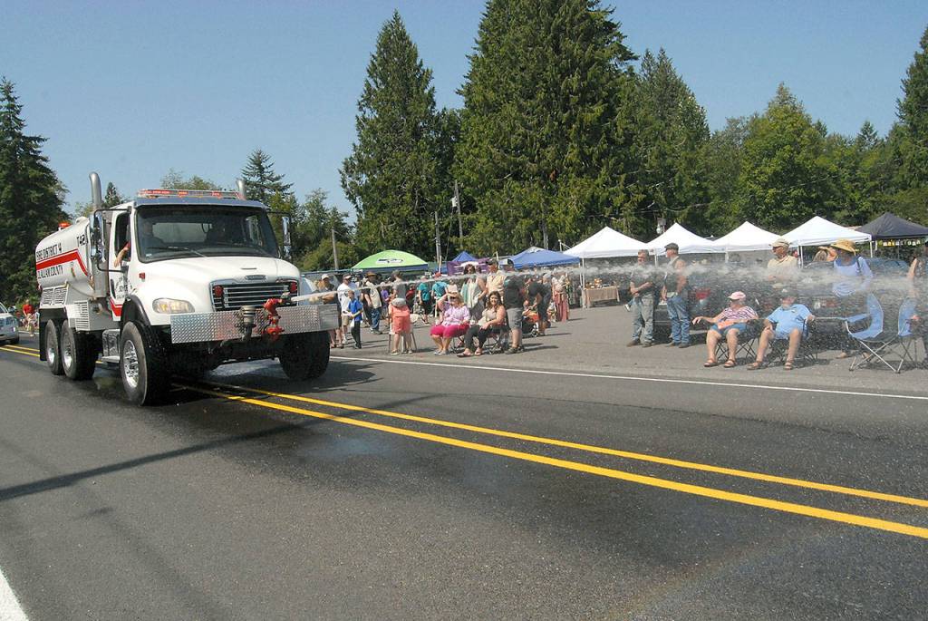 A tanker truck belonging to Clallam Count Fire District 4 sprays water down the parade route on State Highway 112.
