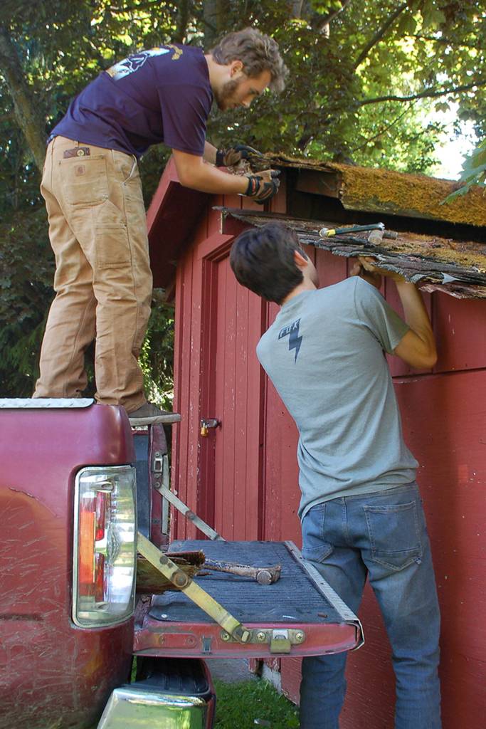 Eagle Scout candidate Ian Thill and Sergio Yanez work on removing a section of the lower roof of the Pioneer Memorial Park storage shed.