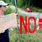 Lissy Andrews of Port Townsend holds a protest sign just off state Highway 20 south of Anderson Lake Road. (Brian McLean/Peninsula Daily News)