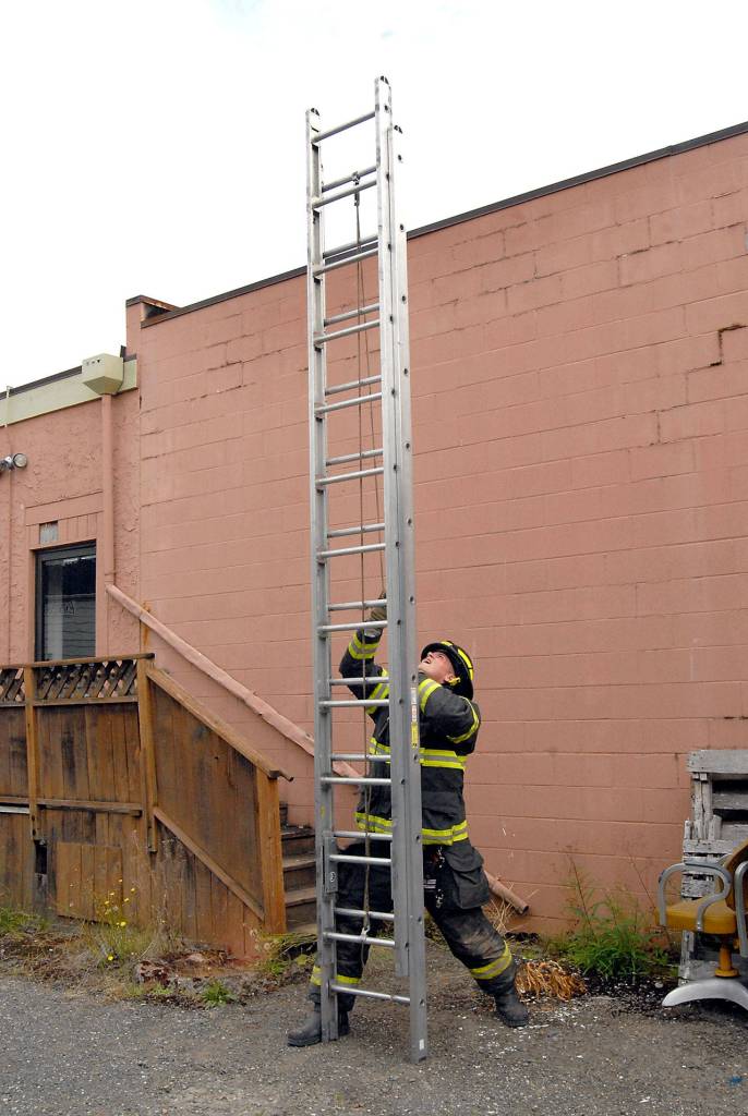 Port Angeles firefighter Chad Schoonhoven practices techniques to raise and lower a fire ladder during a drill at the former Harbor Art gallery on Railroad Avenue in downtown Port Angeles on Tuesday. (Keith Thorpe/Peninsula Daily News)