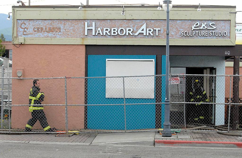 Port Angeles firefighter George Kourdani walks behind construction fencing in front of the former Harbor Art gallery on the Port Angeles waterfront during a training drill in the building Tuesday. (Keith Thorpe/Peninsula Daily News)