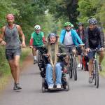 Ian Mackay of Agnew, center, leads a contingent of friends and supporters on bicycles and on foot from his motorized wheelchair along the Olympic Discovery Trail near 18th Street in Port Angeles during Saturdays segment of the three-day Sea to Sound group ride across a portion of the North Olympic Peninsula. (Keith Thorpe/Peninsula Daily News)