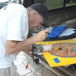 Bob Walter of Port Angeles makes repaires on a novelty radio-controlled airplane make from a piece of plastic painted to look like a pizza box during a flying demonstration hosted by the Port Angeles-based Olympic R/C Modelers. (Keith Thorpe/Peninsula Daily News)