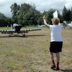 Air Affaire co-founder Emily Westcott of Sequim guides an incoming aircraft to a parking spot at Sequim Valley Airport on Saturday. (Keith Thorpe/Peninsula Daily News)