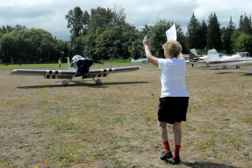 Air Affaire co-founder Emily Westcott of Sequim guides an incoming aircraft to a parking spot at Sequim Valley Airport on Saturday. (Keith Thorpe/Peninsula Daily News)