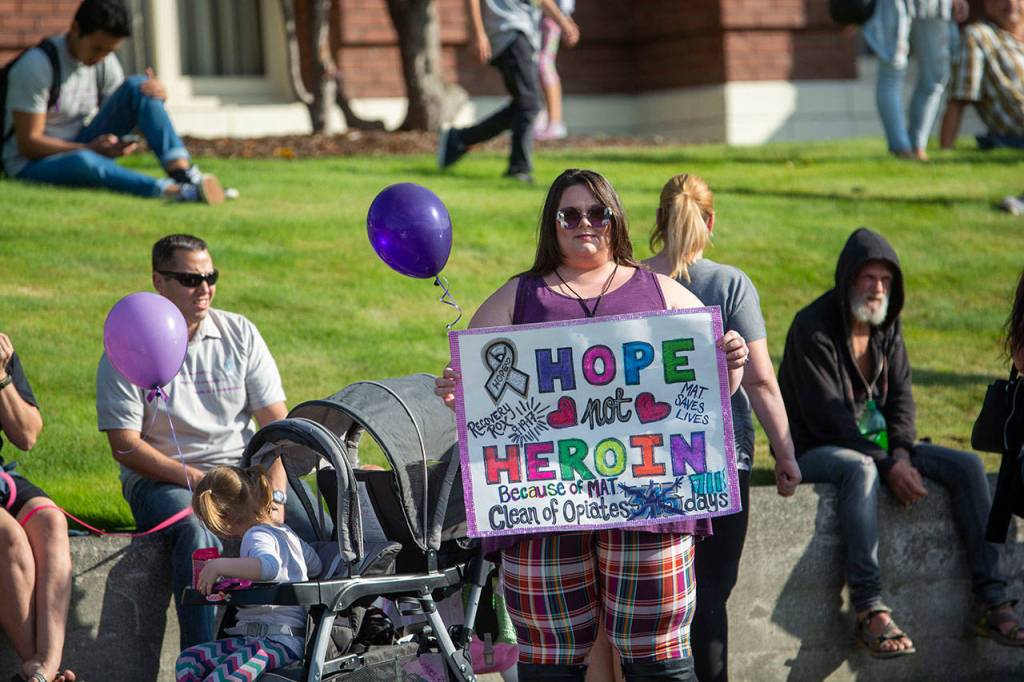 Miranda Beck, who is in recovery from heroin addiction, holds a sign that says she has 711 days free from heroin because of medication-assisted treatment during the fifth-annual Overdose Awareness Day walk in Port Angeles on Saturday. (Jesse Major/Peninsula Daily News)