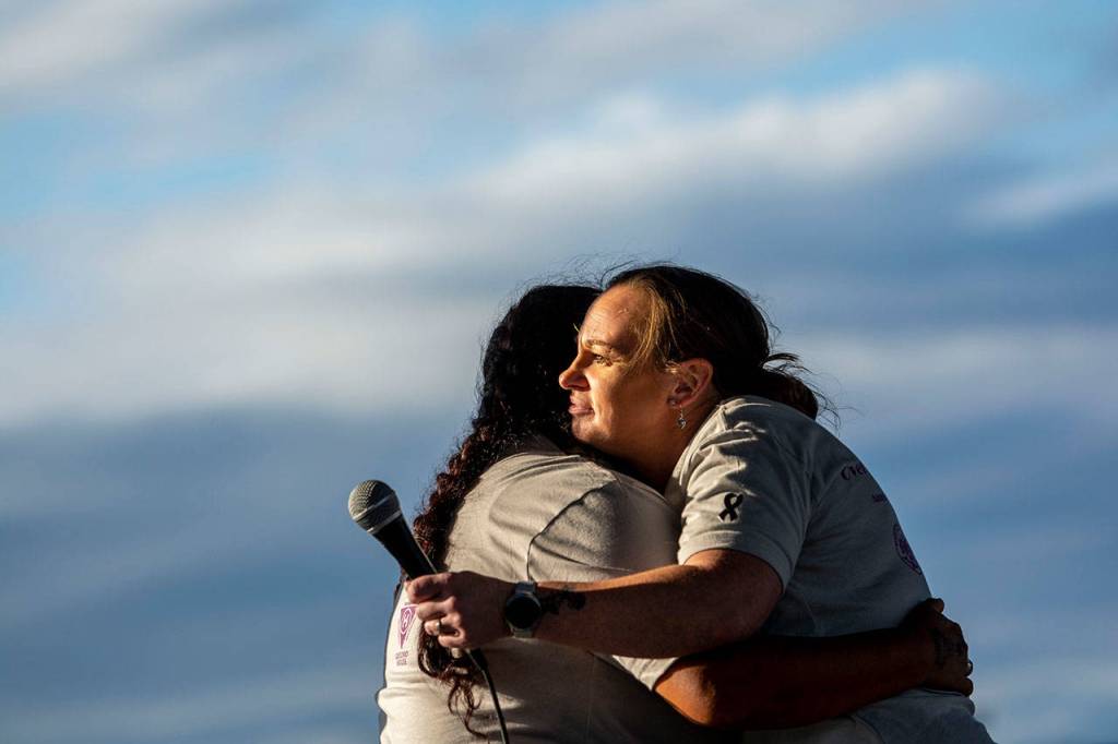 Jessica Elofson, left, embraces Port Angeles Citizen Action Network board member Monica Farris after she shared her story of recovery during the walk. (Jesse Major/Peninsula Daily News)