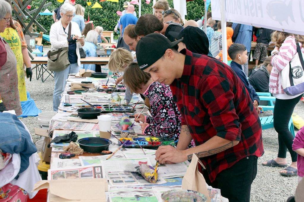 Andrew Eberting paints a fish that will be pressed onto a T-shirt for his daughter while at the Wooden Boat Festival on Saturday. (Zach Jablonski/Peninsula Daily News)