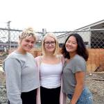 Port Angeles seniors, from left, Kenzie Johnson, Emma Murray and Felicia Che lead a team that has no home pool this season. Behind them, workers are busy rebuilding the William Shore Memorial Pool. (Pierre LaBossiere/Peninsula Daily News)