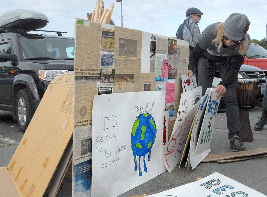 Mindy Gelder of Port Angeles sorts through a collection of signs at the start of Fridays Climate Strike rally in Port Angeles. (Keith Thorpe/Peninsula Daily News)