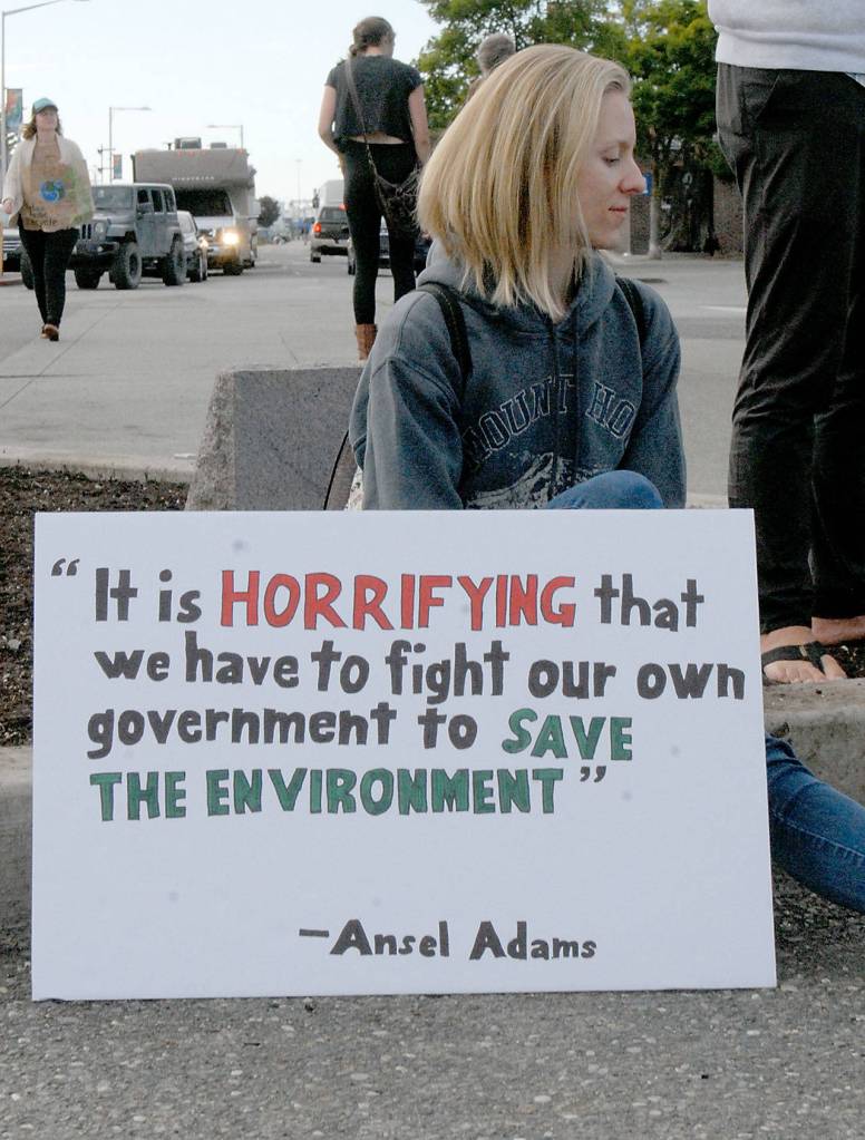 Faith Masimer of Port Angeles sits on a curb near Hollywood Beach in Port Angeles at the start of Fridays Climate Strike. (Keith Thorpe/Peninsula Daily News)