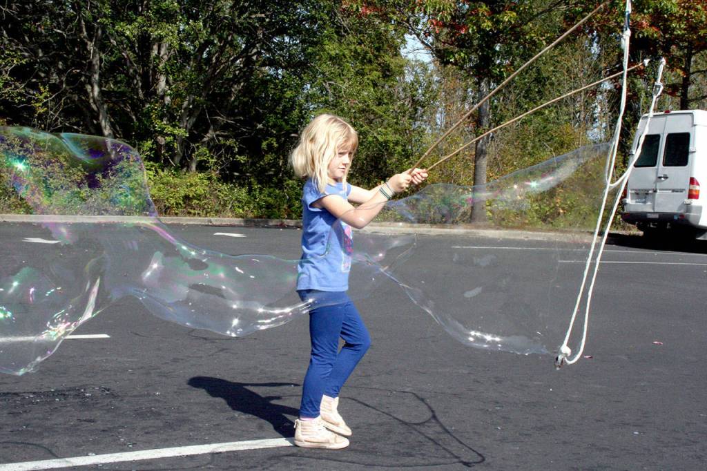 LevynBlu Hamm, 6, makes large bubbles as she runs through the parking lot near the Port Townsend Farmers Market on Wednesday at the Haines Place Park & Ride. (Brian McLean/Peninsula Daily News)