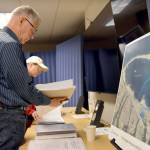 Roger McGinnis, a retired environmental consultant, reviewed Rayonier mill cleanup documents before a presentation Wednesday at a table that included a map delineating cleanup areas in Port Angeles Harbor. (Paul Gottlieb/Peninsula Daily News)