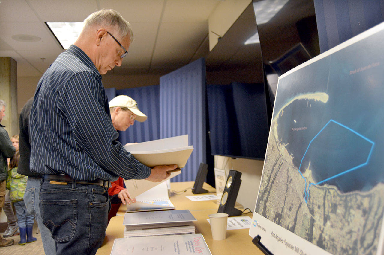 Roger McGinnis, a retired environmental consultant, reviewed Rayonier mill cleanup documents before a presentation Wednesday at a table that included a map delineating cleanup areas in Port Angeles Harbor. (Paul Gottlieb/Peninsula Daily News)