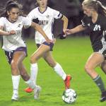 Keith Thorpe/Peninsula Daily News Port Angeles Millie Long, right, charges towards the goal against the defense of North Kitsaps Hannah Knott, left, and Audrey Zinn on Thursday night at Port Angeles Civic Field.