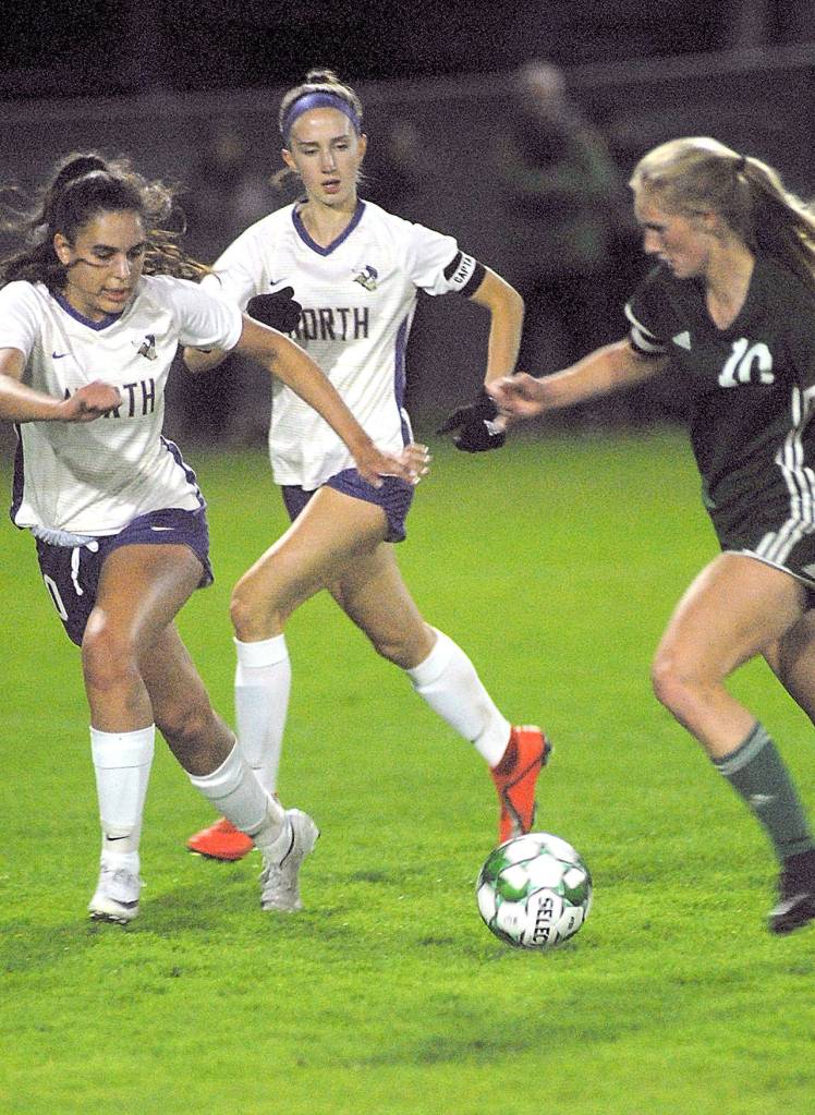 Keith Thorpe/Peninsula Daily News Port Angeles Millie Long, right, charges towards the goal against the defense of North Kitsaps Hannah Knott, left, and Audrey Zinn on Thursday night at Port Angeles Civic Field.