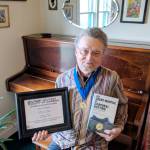 John Nutting displays his award and his memoir in his Port Angeles residence.