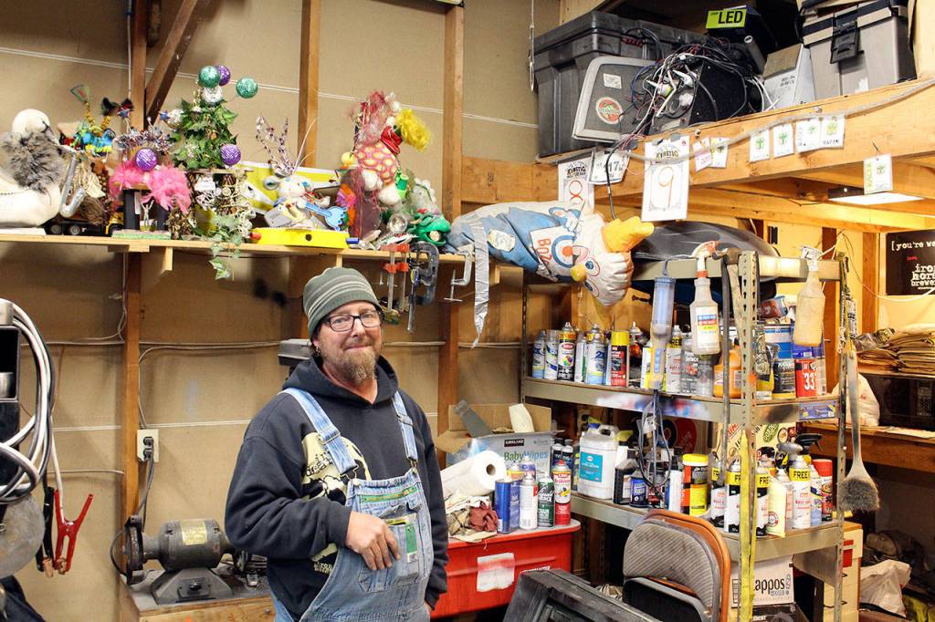 Bertl stands under his shelf of trophies and awards he has earned during his 15-year history of Kinetic Races. (Zach Jablonski/Peninsula Daily News)