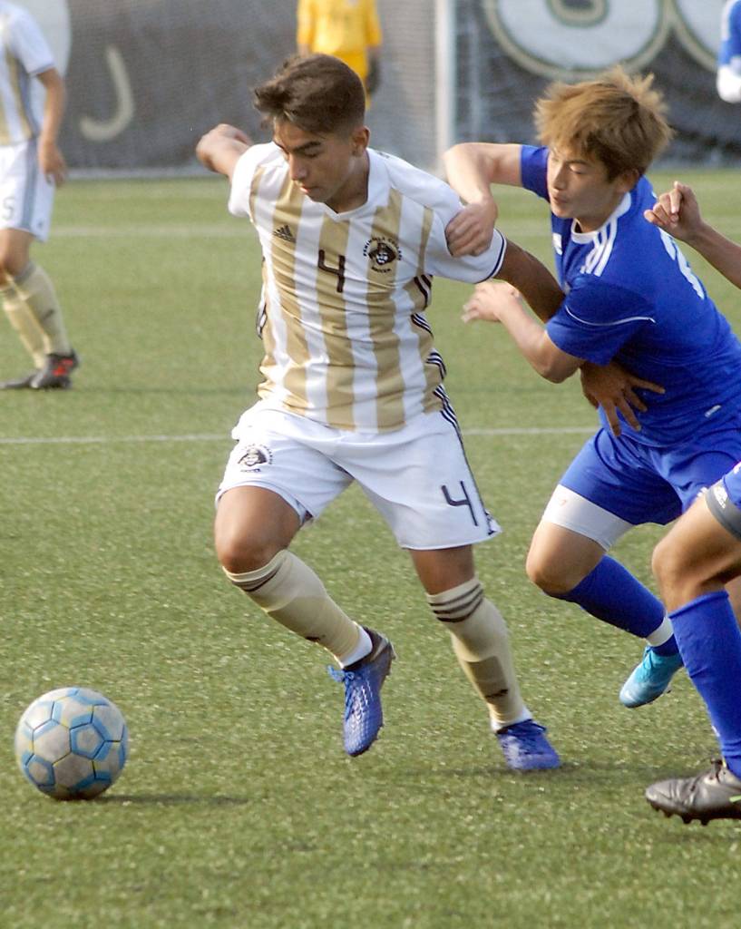 Keith Thorpe/Peninsula Daily News Peninsulas Isael Lopez-Plascencia fends off the advances of Edmonds Wataru Muto on Friday in Port Angeles.